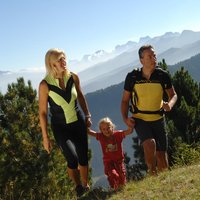 Familientrekking im Fleimstal - Mutter, Vater und Tochter spazieren glücklich im Fleimstal
